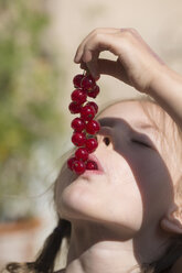 Deutschland, Bayern, Mädchen isst rote Johannisbeeren - SARF000095