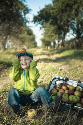 Deutschland, Sachsen, Junge sitzend mit Korb voller Äpfel, lizenzfreies Stockfoto