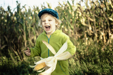 Deutschland, Sachsen, Junge hält Maiskolben und lacht - MJF000311