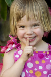 Germany, Baden Wuerttemberg, Girl putting finger on lips, smiling, close up - LVF000191