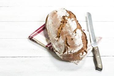 Gebackenes Brot mit Serviette und Messer auf Holztisch, Nahaufnahme - MAEF007160