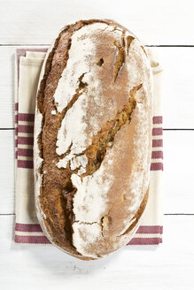 Gebackenes Brot mit Serviette auf Holztisch, Nahaufnahme - MAEF007159