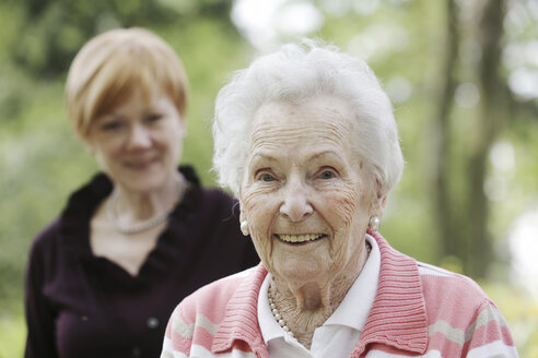 Deutschland, Nordrhein-Westfalen, Köln, Porträt einer lächelnden Seniorin mit einer reifen Frau im Hintergrund - JAT000190