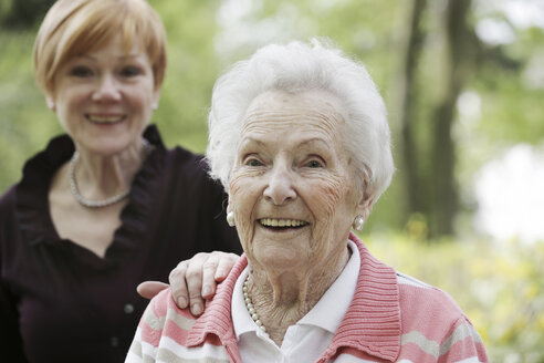 Deutschland, Nordrhein-Westfalen, Köln, Porträt einer lächelnden Seniorin mit einer reifen Frau im Hintergrund - JAT000183