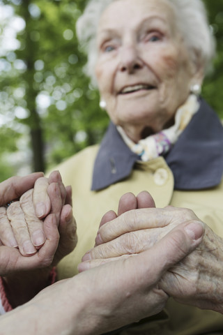 Deutschland, Nordrhein-Westfalen, Köln, Seniorin hält Hände einer reifen Frau, Nahaufnahme, lizenzfreies Stockfoto