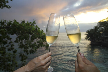 Zwei Menschen halten Champagnerflöten am Strand - KRP000018
