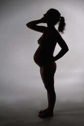 Silhouette einer nackten jungen schwangeren Frau, Studioaufnahme - BFRF000257