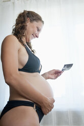Germany, Brandenburg, young pregnant woman holding sonogram - BFRF000270