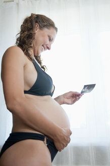Deutschland, Brandenburg, junge schwangere Frau mit Sonogramm - BFRF000270