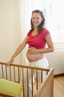 Deutschland, Brandenburg, junge schwangere Frau an der Krippe stehend - BFRF000271