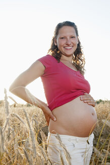 Deutschland, Brandenburg, junge schwangere Frau im Kornfeld stehend - BFRF000274