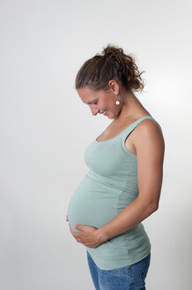 Lächelnde junge schwangere Frau, Studioaufnahme - BFRF000283