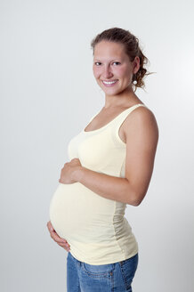 Lächelnde junge schwangere Frau, Studioaufnahme - BFRF000284