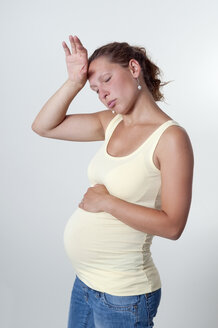 Erschöpfte junge schwangere Frau, Studioaufnahme - BFRF000285