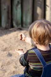 Deutschland, Kiel, Mädchen spielt mit Sand auf Spielplatz, von hinten - JFEF000169