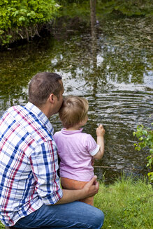 Deutschland, Kiel, Mädchen steht mit seinem Vater an einem Teich und füttert Enten - JFEF000171