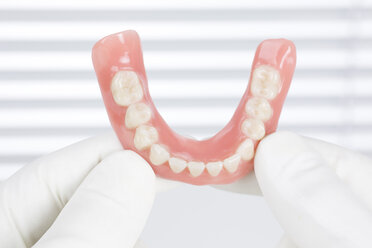 Germany, Freiburg, Dentist holding dentures, close up - DRF000082