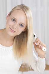 Porträt einer jungen Frau, die ihr Haar bürstet, lächelnd - DRF000127