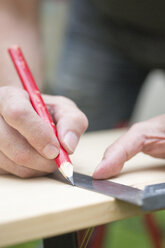 Germany, Freiburg, Mature man measuring wooden board, close up - DRF000095