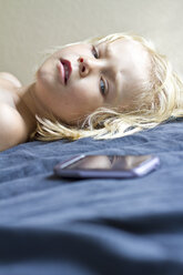 Deutschland, Kiel, Mädchen auf Bett liegend mit Smartphone, Nahaufnahme - JFEF000184