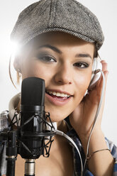 Porträt einer jungen Frau, die in ein Mikrofon singt, lächelnd - FKF000217