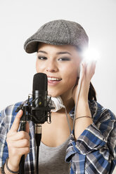 Porträt einer jungen Frau, die in ein Mikrofon singt, lächelnd - FKF000218