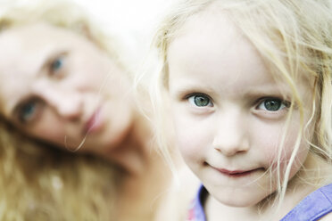 Germany, North Rhine Westphalia, Cologne, Portrait of girl biting lips while her mother in backgroud, close up - JATF000253