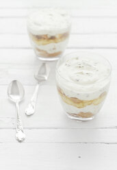 Two glasses of marshmallow, tiramisu, chocolate and banana flavour with spoon on wooden table, close up - CZF000037
