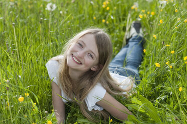 Germany, Bavaria, Portrait of girl lying on meadow, smiling - CRF002468