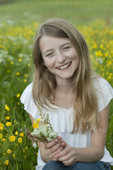 Germany, Bavaria, Portrait of girl holding flowers, smiling - CRF002465