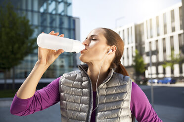 Athletic brunette woman drinking from bottle - SU000005