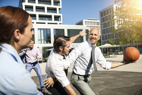 Group of businesspeople playing basketball outdoors - SU000040