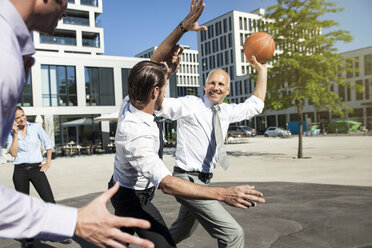 Gruppe von Geschäftsleuten spielt Basketball im Freien - SU000028
