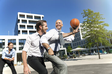 Gruppe von Geschäftsleuten spielt Basketball im Freien - SU000027