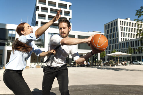 Businessman and businesswoman playing basketball outdoors - SU000023