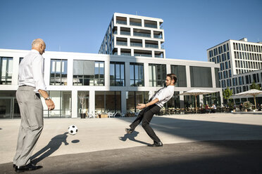 Zwei Geschäftsleute spielen Fußball im Freien - SU000051