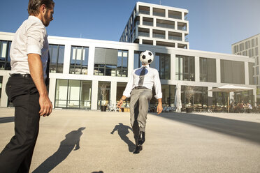 Two businessmen playing soccer outdoors - SU000052