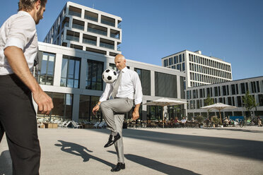 Two businessmen playing soccer outdoors - SU000053