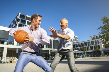 Zwei Geschäftsleute spielen Basketball im Freien - SU000054