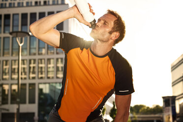 Athletic man outdoors drinking from bottle - SU000016