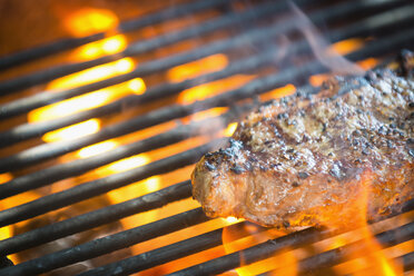 Striploin Steak grilling over hot fire, close up - ABAF000989