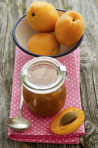 Aprikosenmarmelade mit einer Schale mit Aprikosen auf einem Holztisch, Nahaufnahme, lizenzfreies Stockfoto