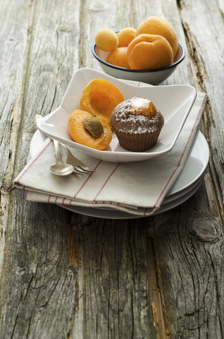 Schalen mit Aprikosen, Muffins und Schokolade auf einem Holztisch, Nahaufnahme, lizenzfreies Stockfoto