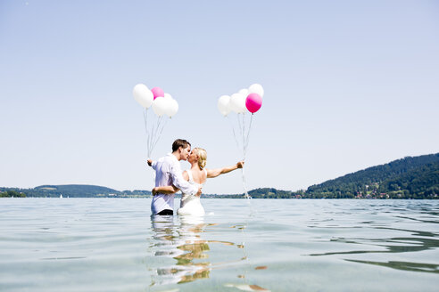 Deutschland, Bayern, Tegernsee, Hochzeitspaar im See stehend, küssend - RFF000092