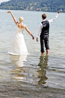 Deutschland, Bayern, Tegernsee, Hochzeitspaar im See stehend, mit Handschellen - RFF000106