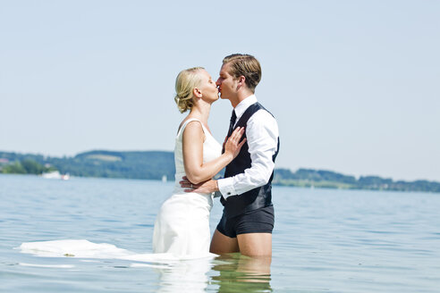 Deutschland, Bayern, Tegernsee, Hochzeitspaar im See stehend, küssend - RFF000107