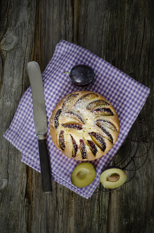 Pflaumenkuchen mit Pflaumen und Serviette auf Holztisch, Nahaufnahme, lizenzfreies Stockfoto