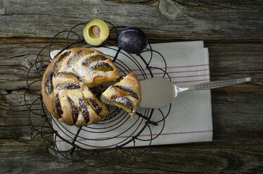 Hausgemachter Pflaumenkuchen mit Kühlgestell und Tortenheber auf Holztisch, Nahaufnahme - OD000331