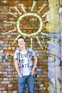 Germany, Berlin, Boy standing in front of brick wall with graffiti - MVC000016