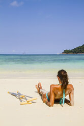 Thailand, Koh Surin island, woman with crutches lying at the white sandy beach - MBEF000725